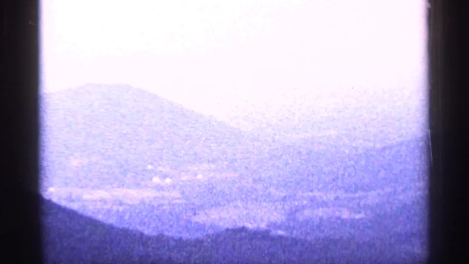 1964 West Virginia 8mm frame with soft, overexposed haze over layered mountain ridges and a faint valley below.