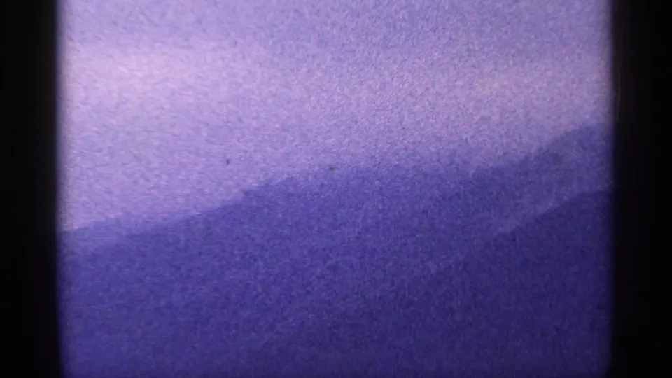 1964 West Virginia 8mm view of layered purple mountain slopes receding into haze beneath a pale lavender sky.