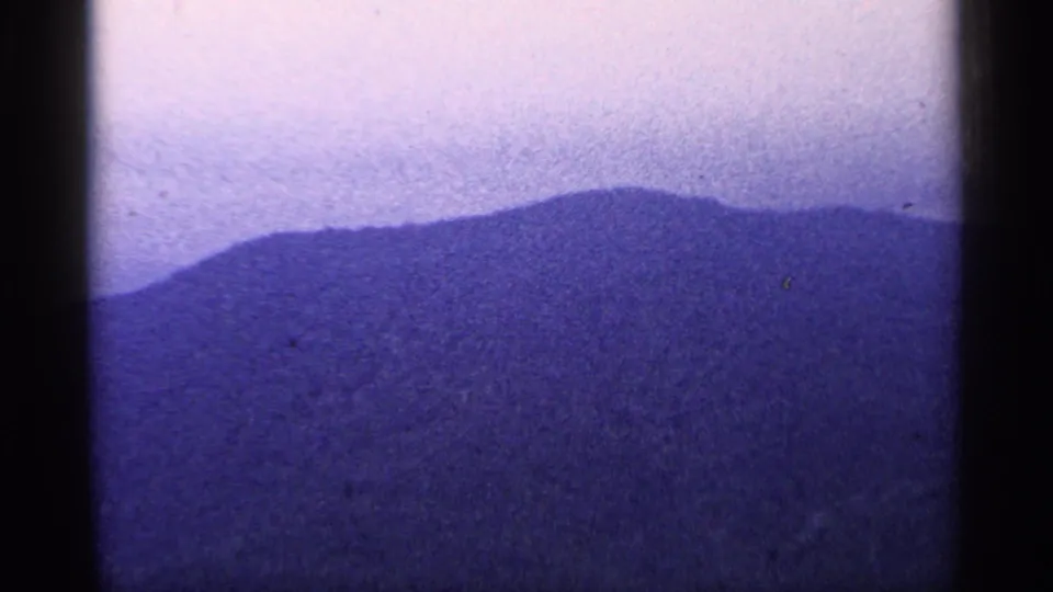 The final frame shows a blue-toned mountain ridge and pale sky, with visible grain and dark 8mm frame borders.
