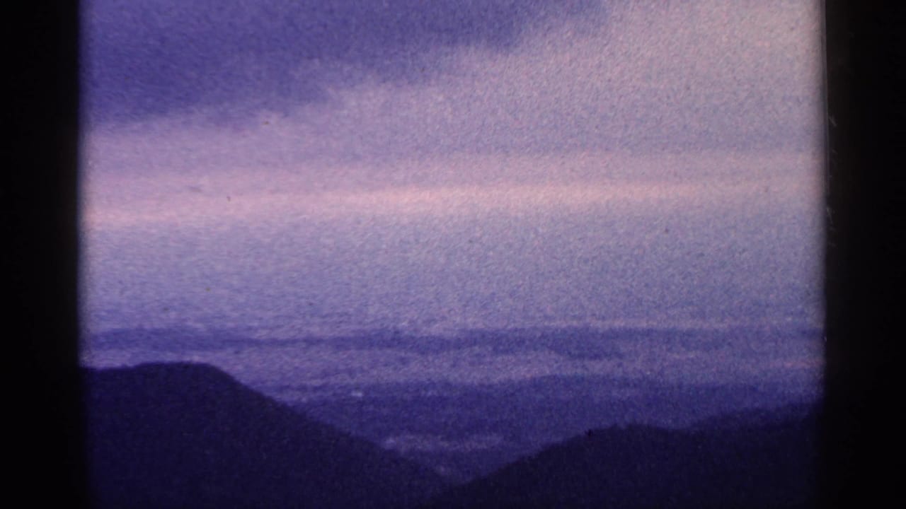 Distant mountain valley framed by dark 8mm film borders.