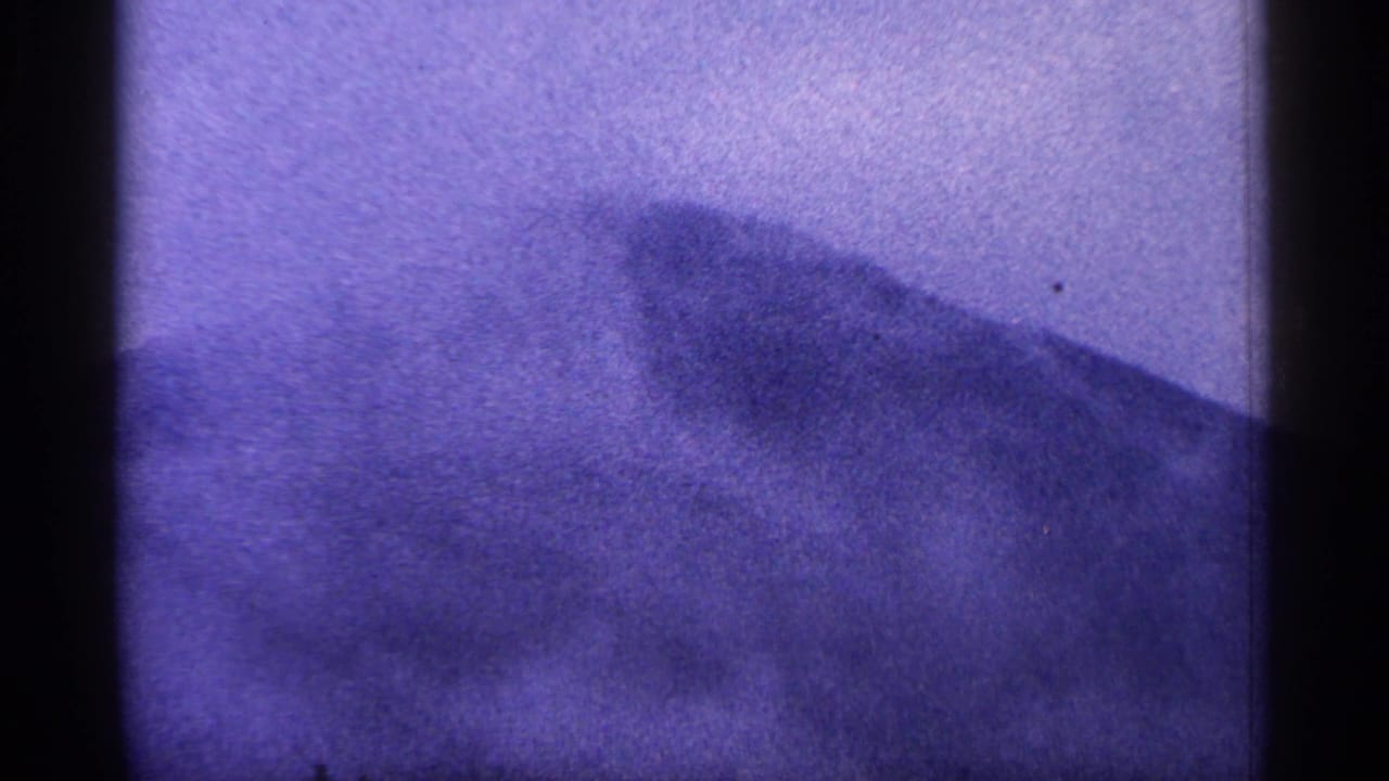 Purple-tinted 8mm view of a dark West Virginia mountain ridge fading into haze, with rounded film-frame edges.