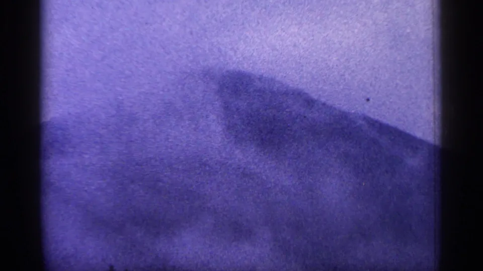 Purple-tinted 8mm view of a dark West Virginia mountain ridge fading into haze, with rounded film-frame edges.