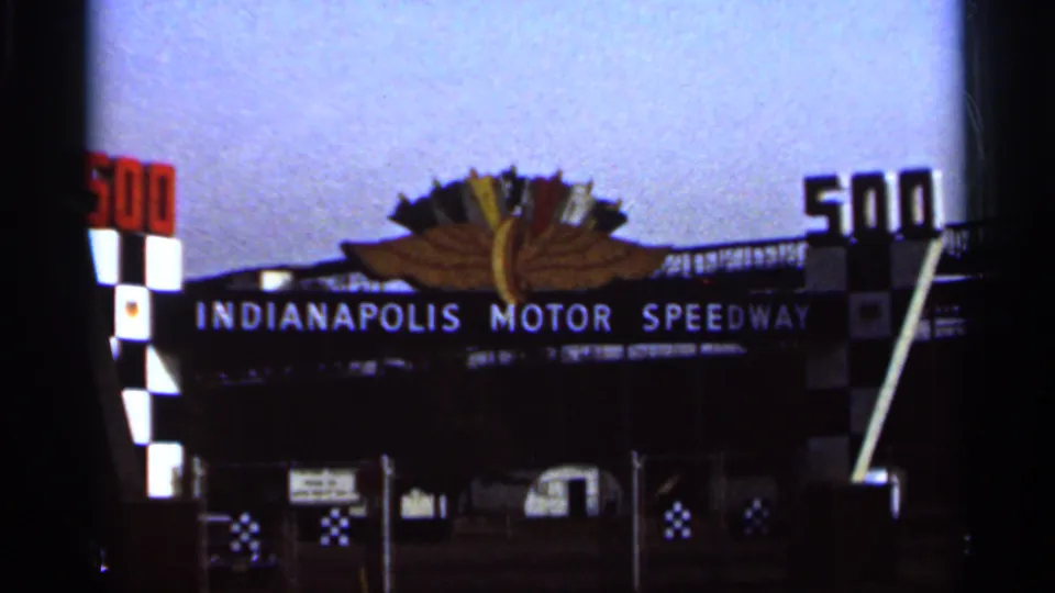 Later 8mm frame of the Indianapolis Motor Speedway entrance, with the 500 numerals, checkered columns, and central emblem visible.