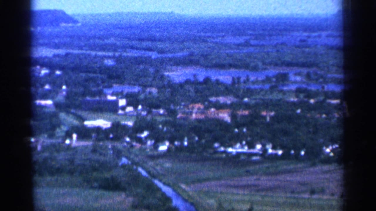 1965 Duluth-area 8mm view over trees, scattered buildings, open fields, and a hazy horizon.