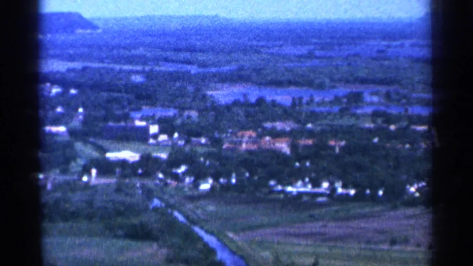 1965 Duluth-area 8mm view over trees, scattered buildings, open fields, and a hazy horizon.