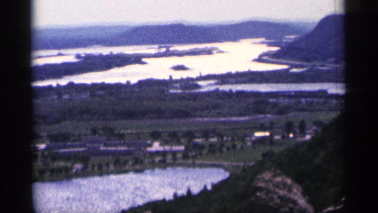 Bright winding waterways, low hills, roads, and shoreline buildings seen from above.