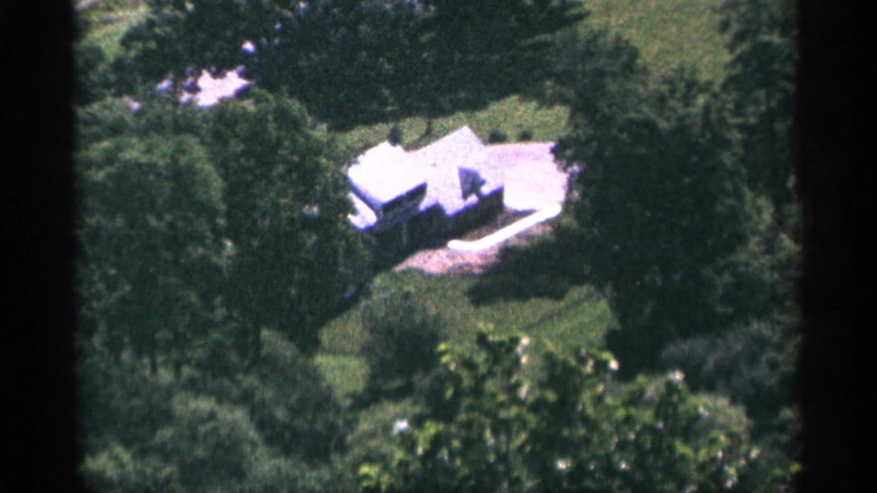 White house and surrounding trees seen from above at a distance.