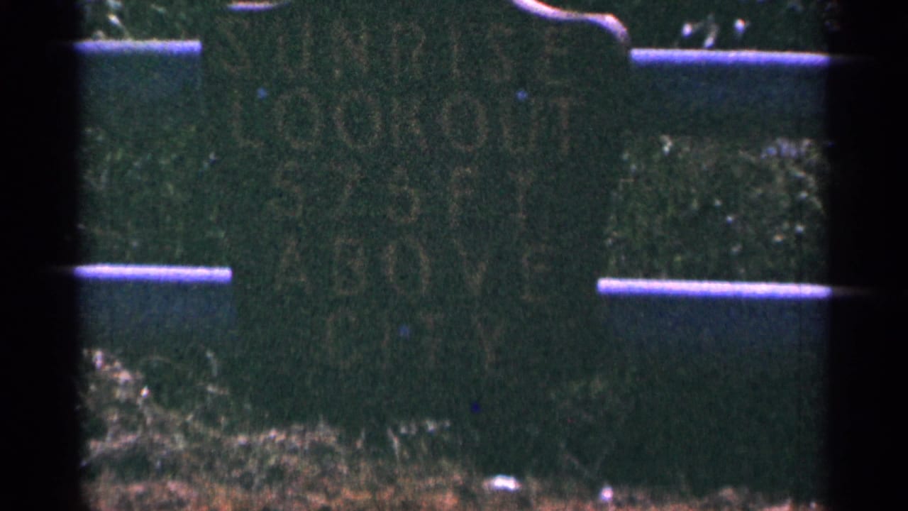 A weathered green sign in Duluth reads Sunrise Lookout and appears to note a height above the city.