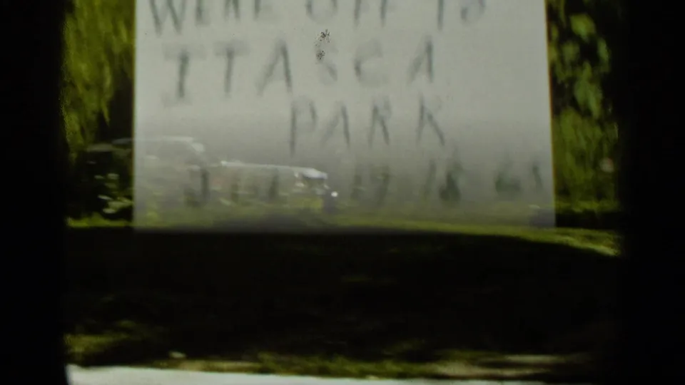 A large pale handwritten sign, possibly reading as a park marker, appears in shade with trees and lawn in the 1965 Minnesota footage.