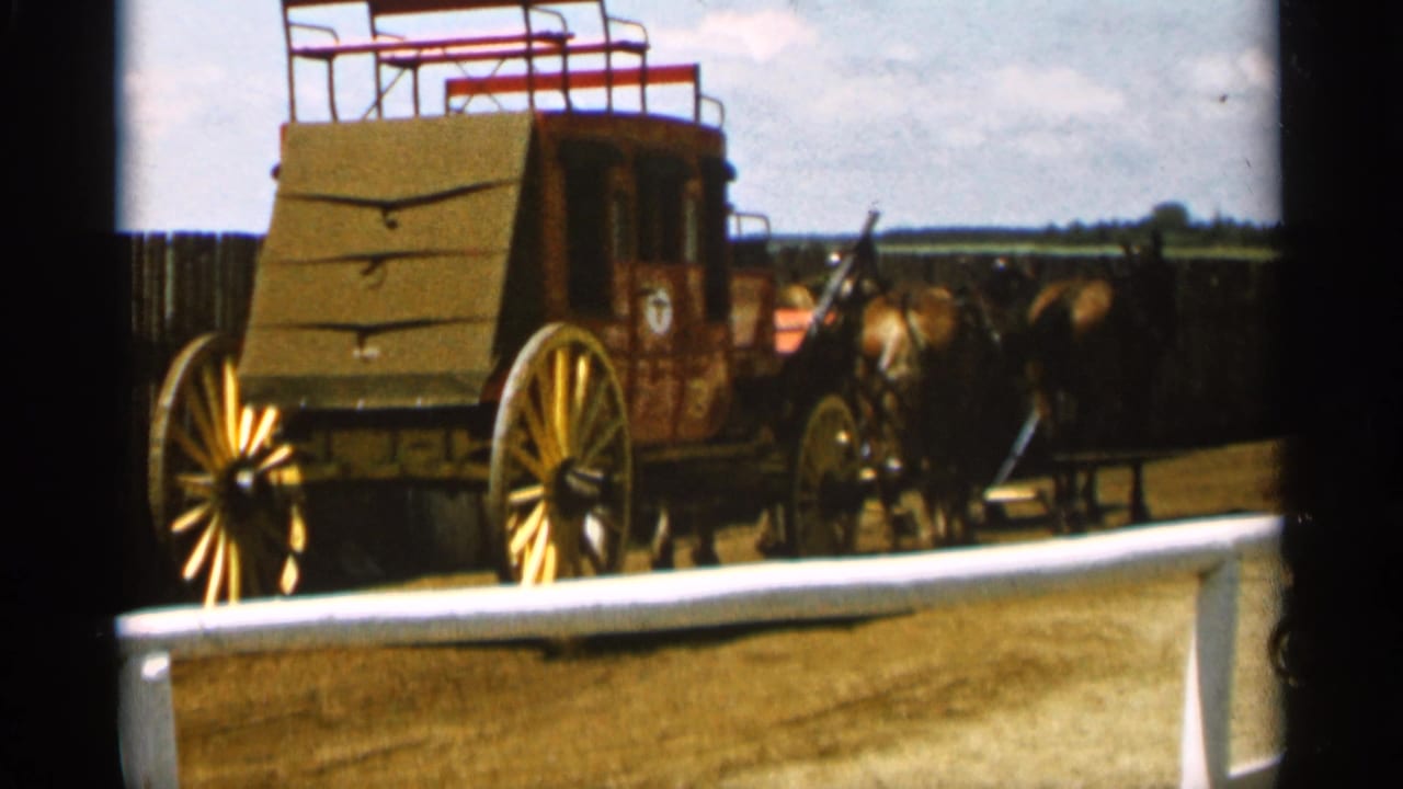 Stagecoach and team of horses seen from a similar angle across a lot.