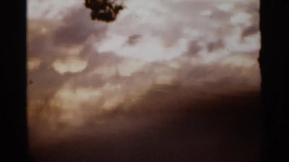 1965 Duluth 8mm frame showing a hazy sepia-toned sky or pond reflection with soft cloud forms.