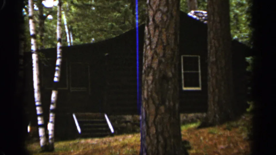 A dark wood cabin among birch and pine trees in Duluth, Minnesota, shown in 1965 8mm home-movie footage.