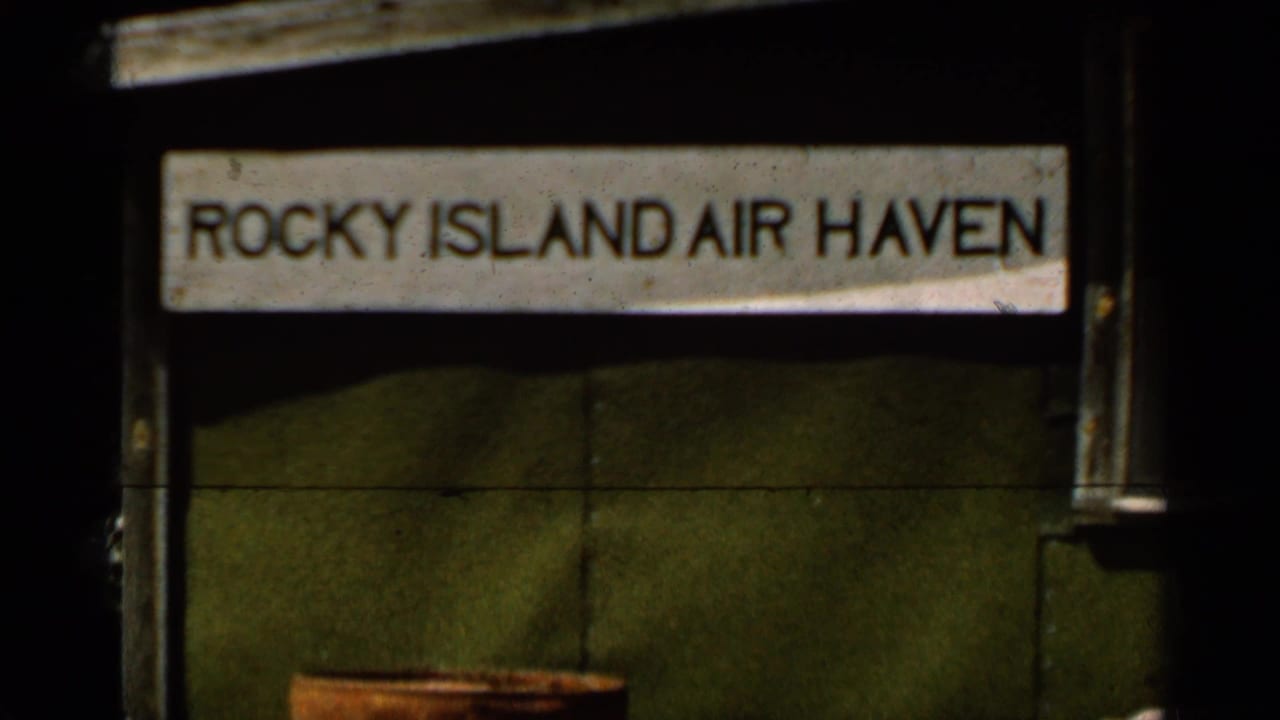 Weathered sign reading Rocky Island Air Haven on a dark waterside structure.