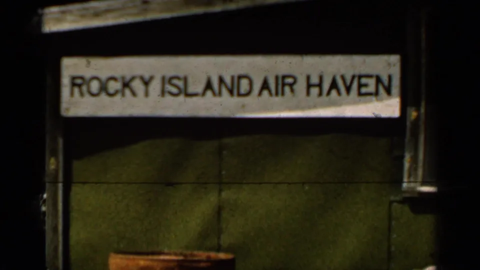 Close view of a Rocky Island Air Haven sign on a dark structure, filmed in 1965 home-movie footage near Duluth, Minnesota.