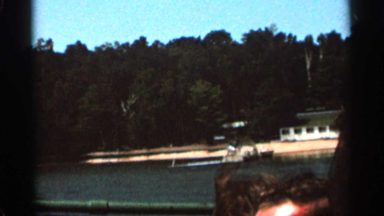 Boat near a wooded shoreline with a partial person visible at the lower edge.
