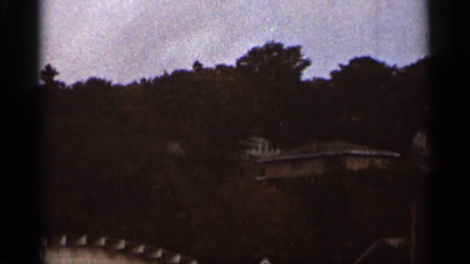 Soft 8mm view of Duluth rooftops tucked into a wooded hillside under muted gray light.