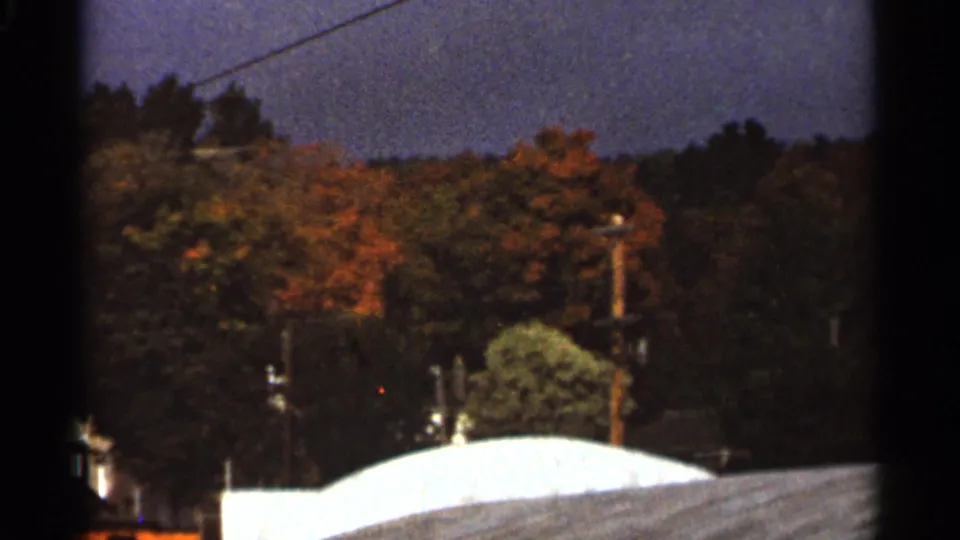 1965 Duluth frame with a power line, utility pole, fall-tinted trees, and pale residential roofs.