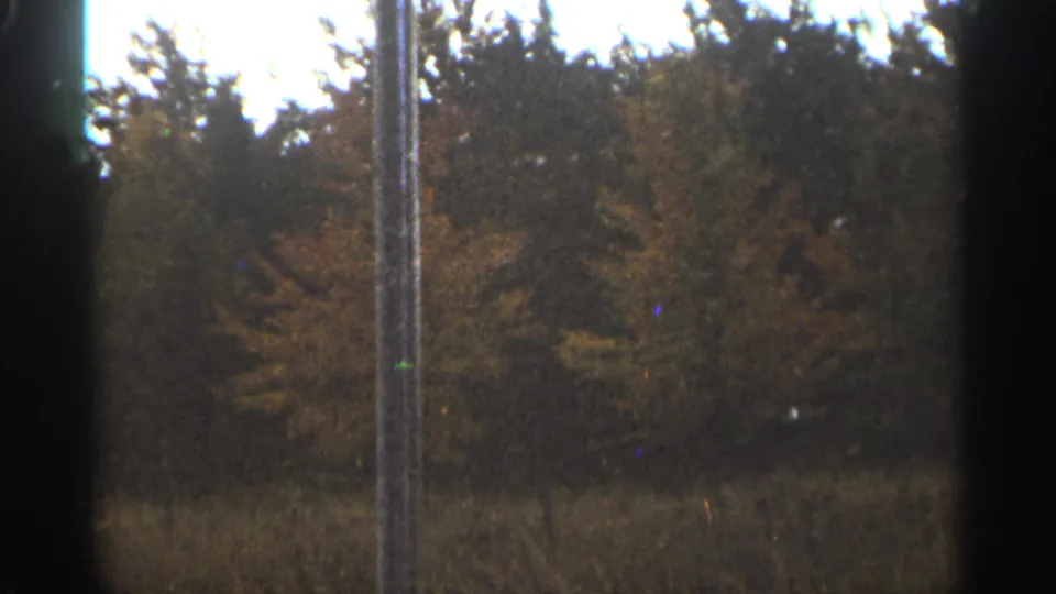 1965 Duluth-area landscape frame with autumn woods, grassy field, pale sky, and a vertical foreground pole.