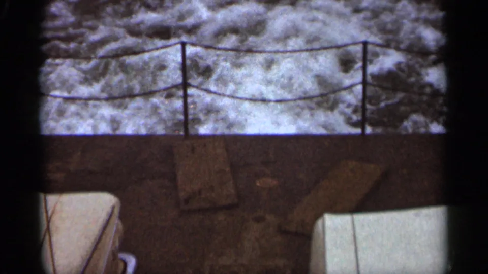 Duluth lakeshore cutaway showing rough water behind a rope railing, with rocks and dark 8mm frame edges visible.