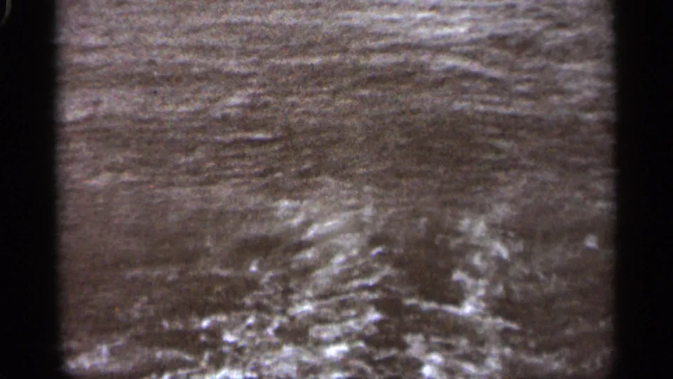 1965 Duluth home-movie frame focused closely on turbulent water and foam from a moving boat.