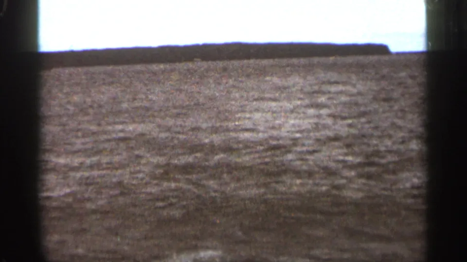 1965 Duluth 8mm frame showing open water and a low distant shoreline from a moving boat.