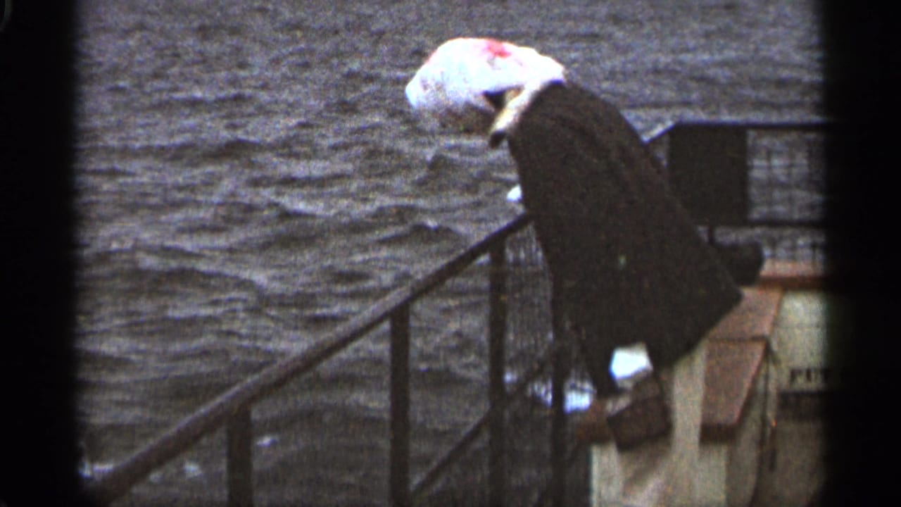 Woman in a headscarf and dark coat leans over a boat railing beside dark water.