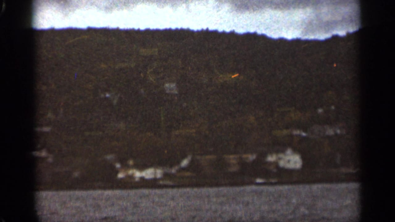 Distant shoreline with white buildings below a dark treeline across open water.