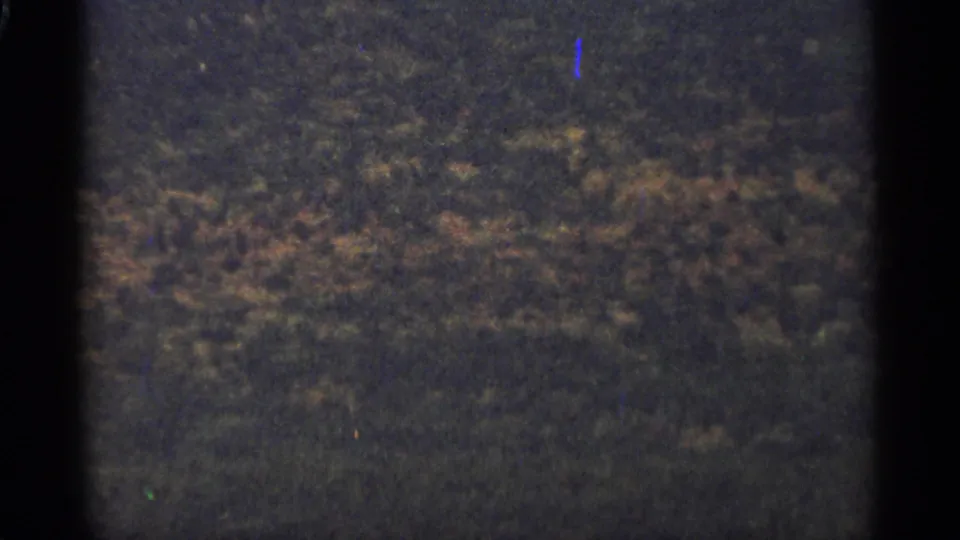 A dim 8mm frame from Duluth, Minnesota, with textured hillside or treeline detail and strong film grain along the gate edges.