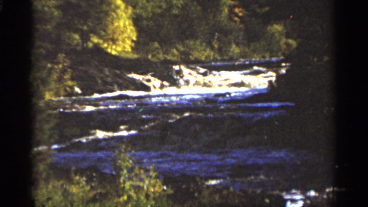 River water rushing across rocks with trees and dark frame edges around the scene.