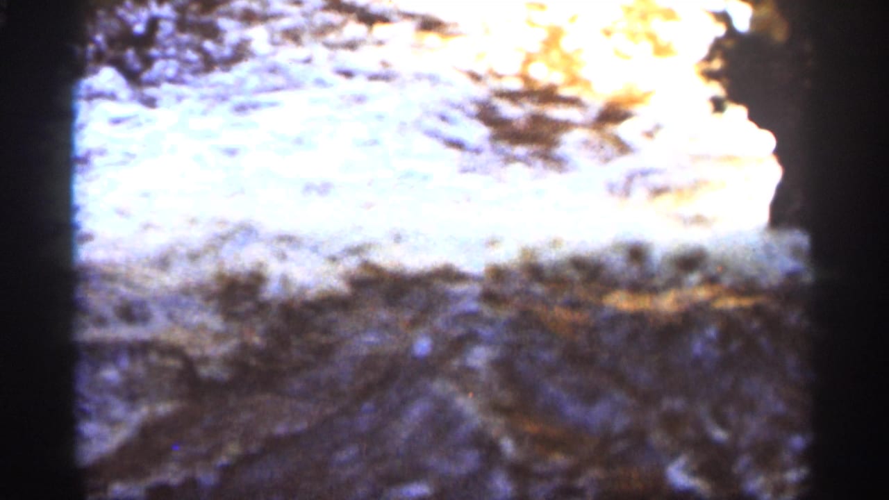 Rippling creek water with bright sunlight reflecting over rocks.