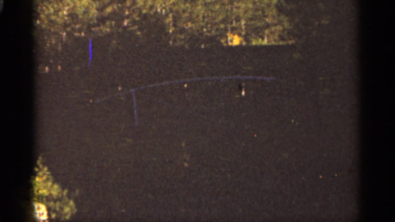 Dark nighttime water feature with faint curved structure and film scratches.