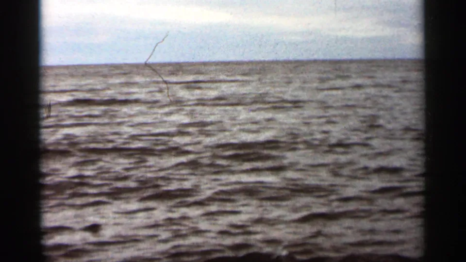 1965 Duluth-area 8mm frame of open rippled water and pale sky, with a faint distant horizon line.