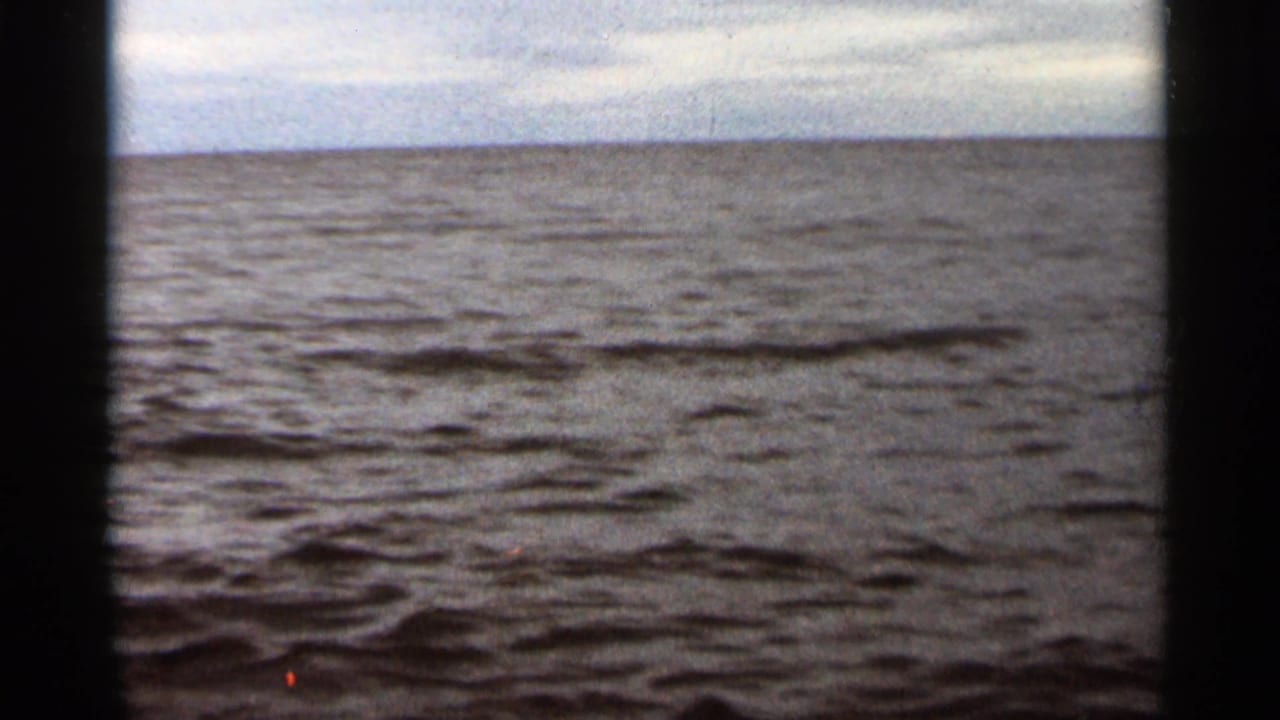 Calm lake water beneath an overcast horizon with dark 8mm frame edges.