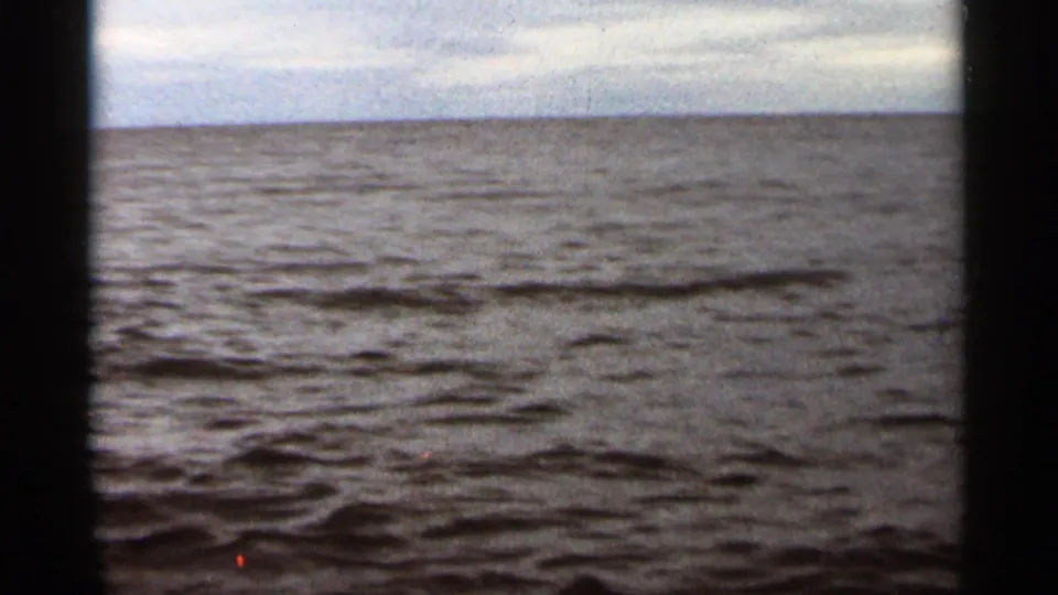 1965 8mm view of Lake Superior at Duluth, showing gentle water under a pale overcast sky.