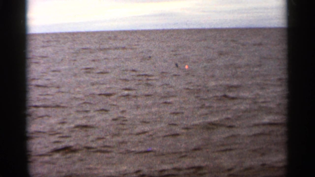 Wide view of rippled lake water and a pale sky through 8mm film edges.