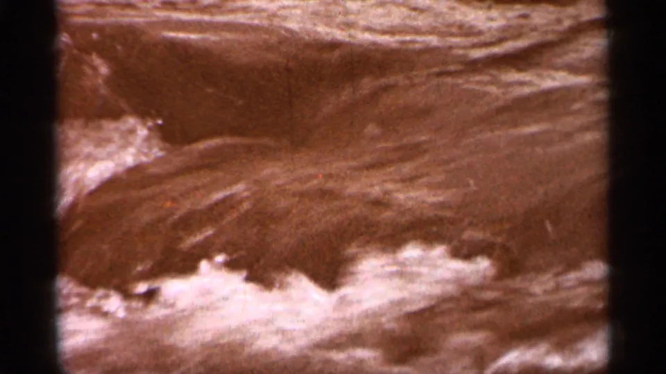 Close 1965 8mm view of Lake Superior water near shore, with reddish color cast and small foamy waves.