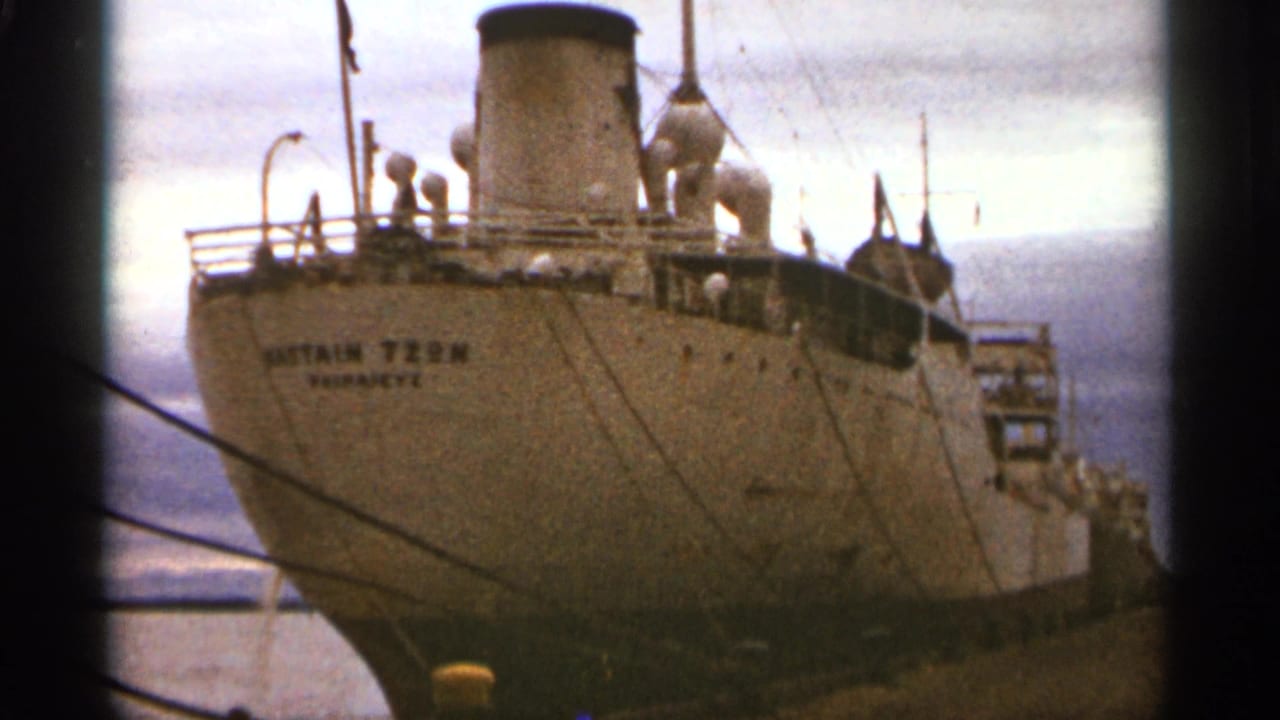 Stern of a docked cargo ship with the name Captain Tzon visible under a cloudy sky.