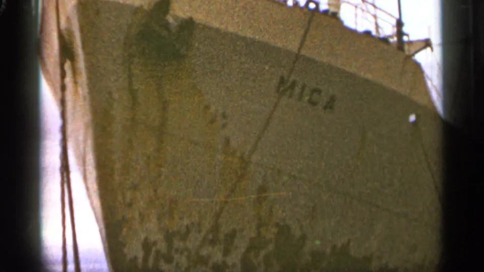 1965 Duluth 8mm frame showing the Mica bow and stained hull surface at close range in a cloudy harbor setting.