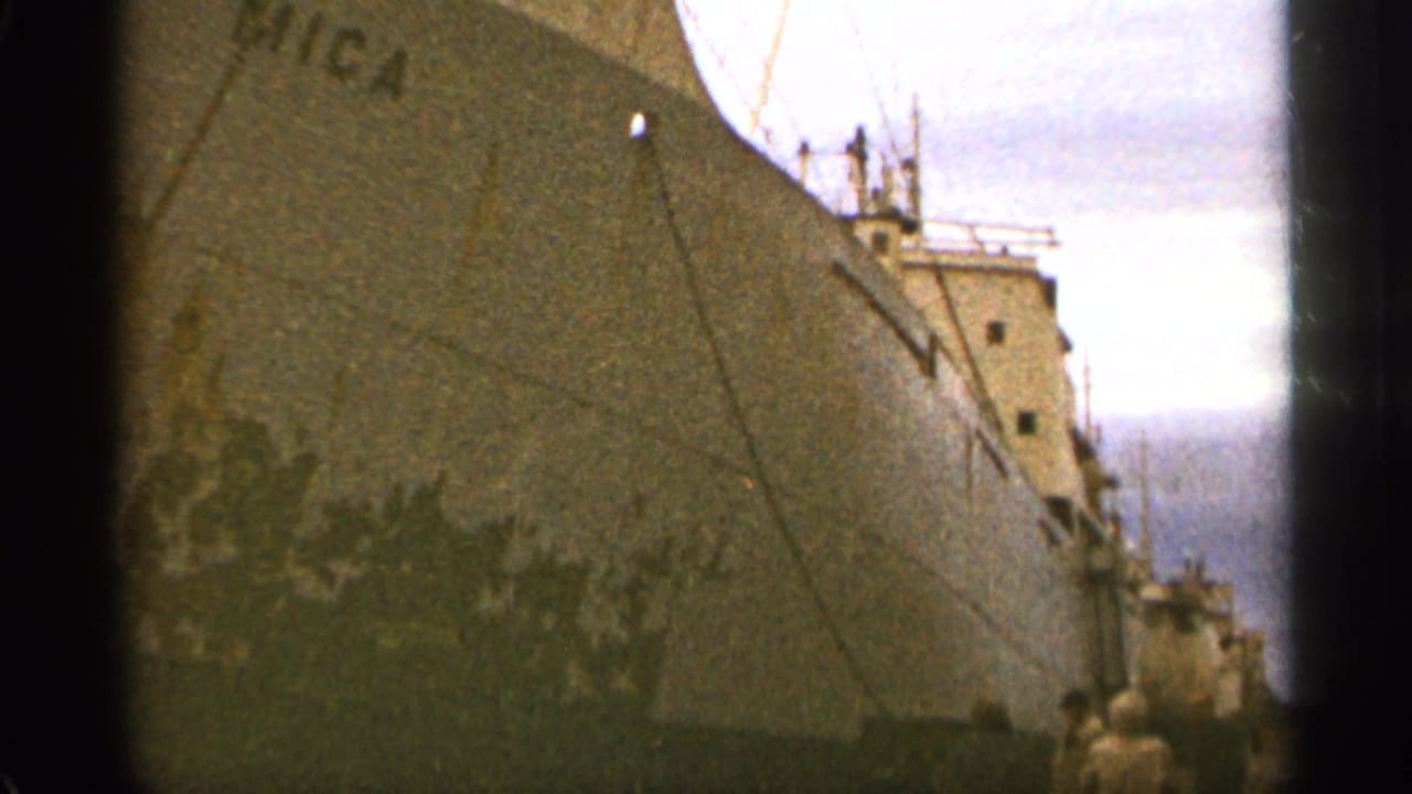 Cargo ship bow and upper structure beside the pier with the MICA name partly visible.