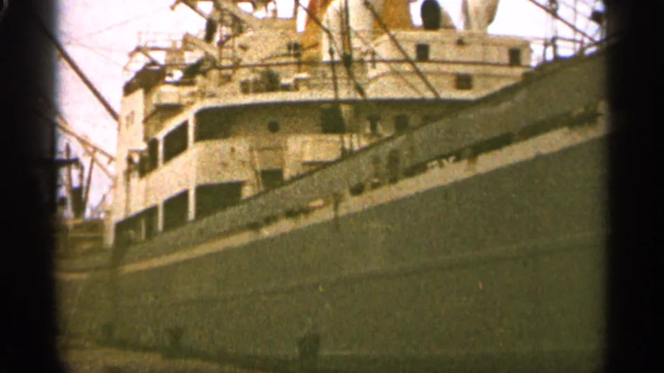 Close dock-level 8mm frame of a large cargo ship in Duluth, with cranes and rigging rising behind the hull.