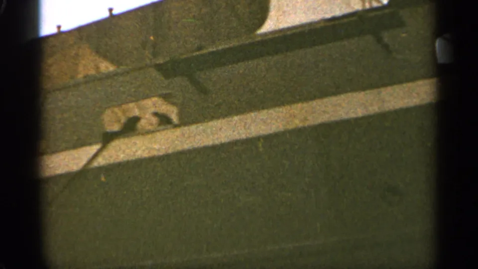 Final 1965 Duluth frame showing the ship's railing, deck edge, dark hull, and a shadowed upper structure in close view.