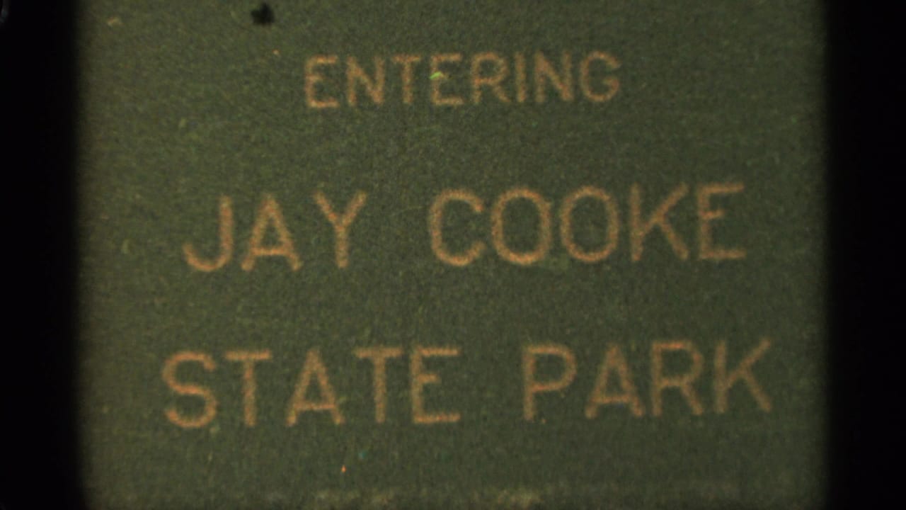 Green sign reading ENTERING JAY COOKE STATE PARK in gold lettering.