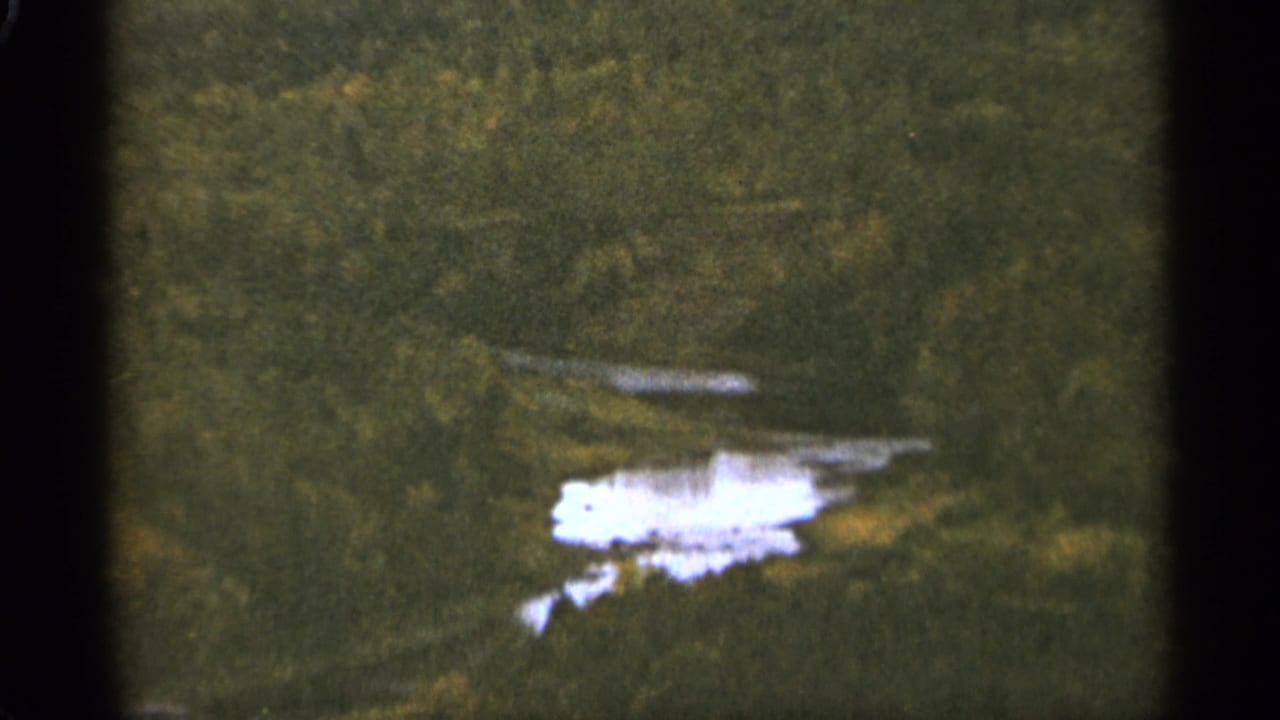 Distant wooded valley with a bright reflective water body near the lower frame.