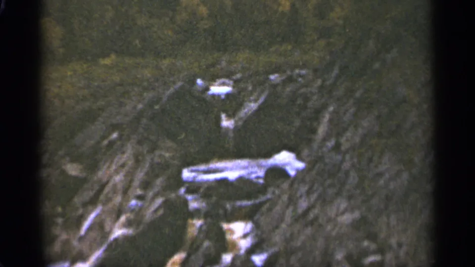 1965 Duluth frame of rocky terrain and dense ground cover, seen through a soft and grainy 8mm scan.