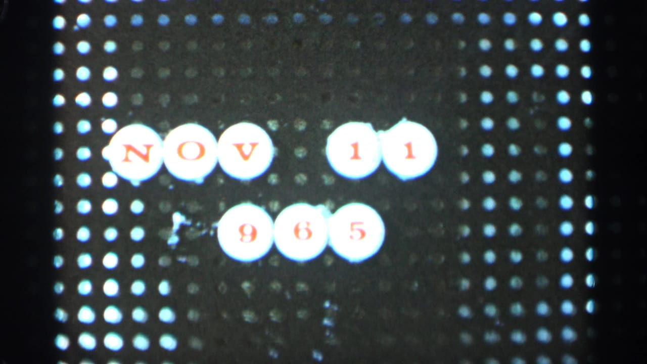 Pegboard with white circular markers spelling NOV 11 965 in red lettering.