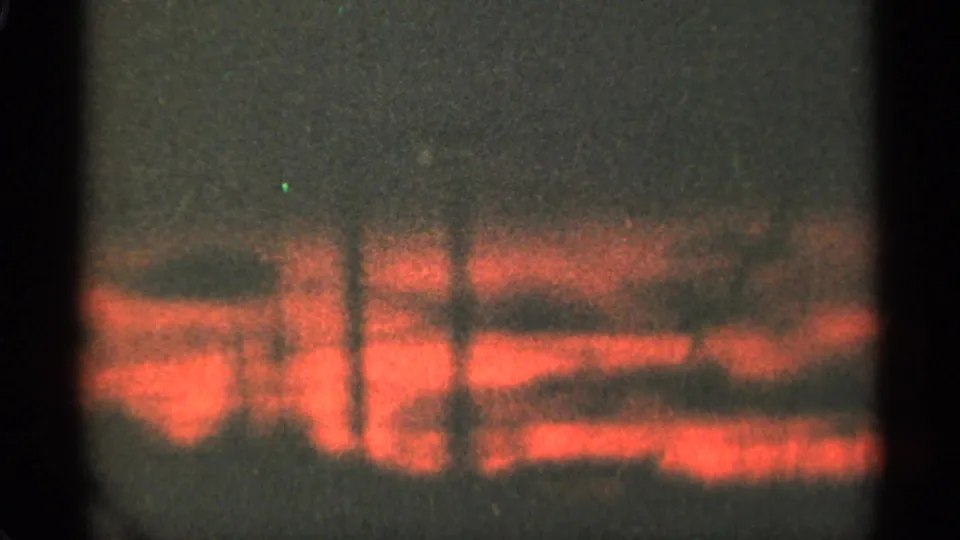 1965 Duluth 8mm frame showing a red-orange sunset broken by dark cloud bands above trees.