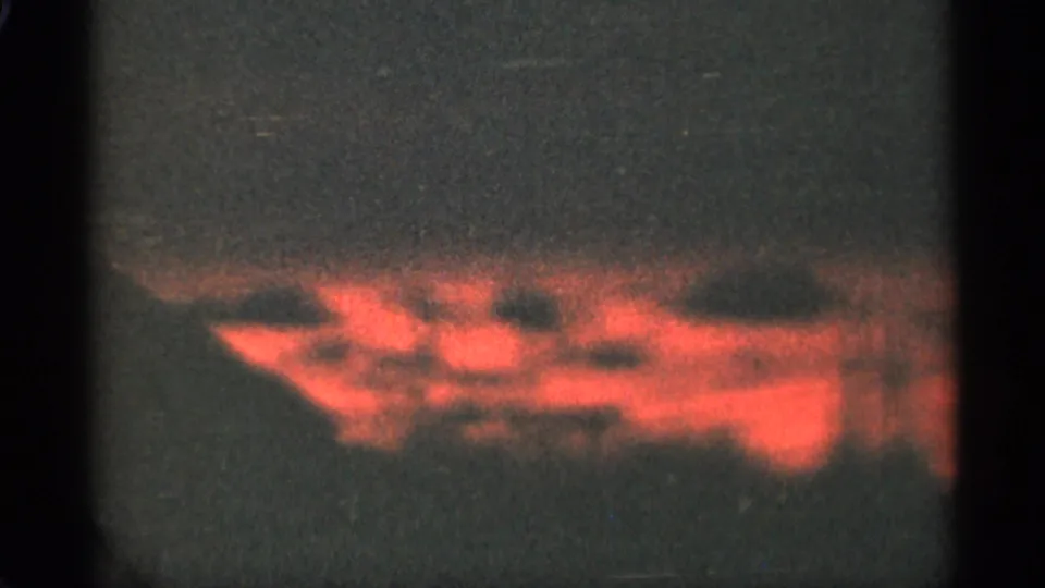 1965 Duluth 8mm frame showing a low red-orange sunset cloud mass below a muted, grainy sky.