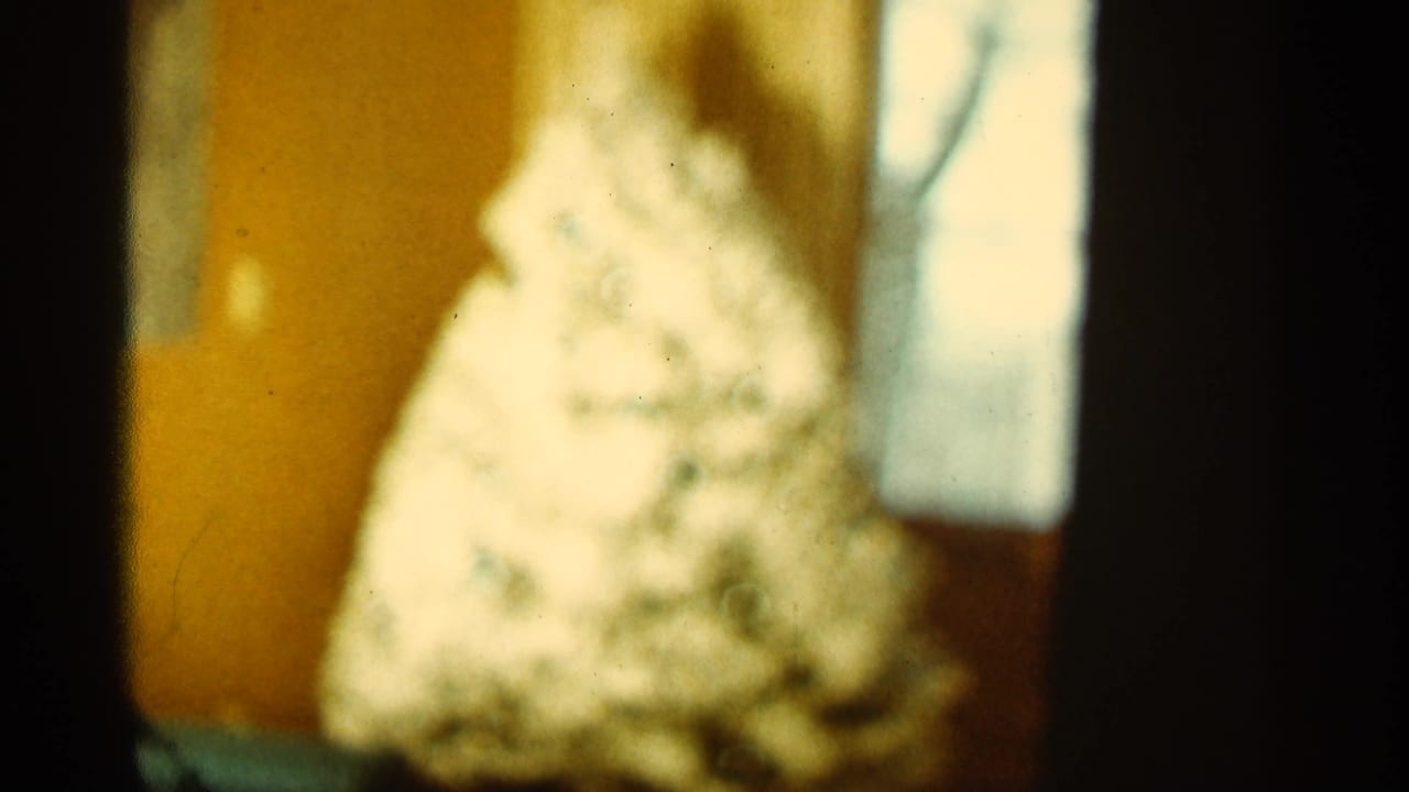Blurred white cone-shaped object in a warm room corner with dark film edge.