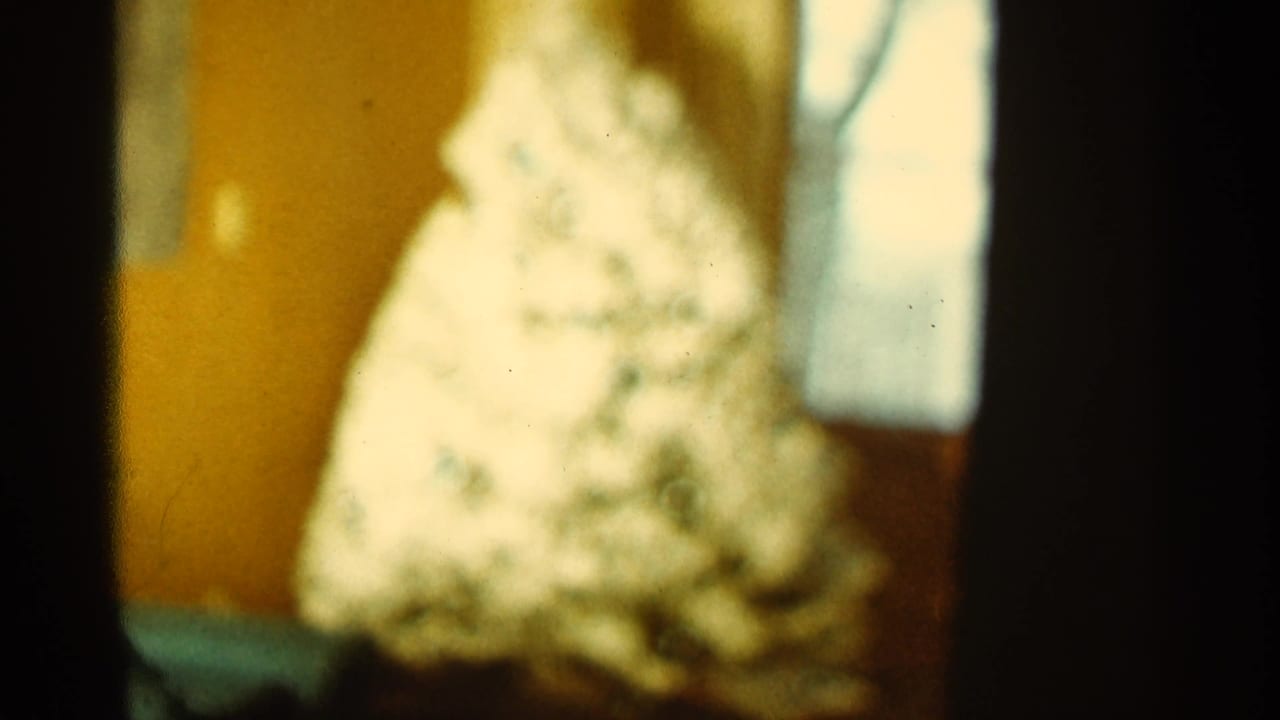 Blurred white cone-shaped object beside a bright vertical opening in a yellow room.