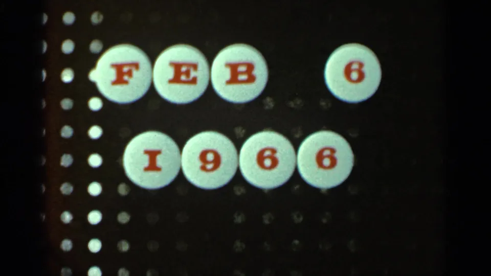 Dated 8mm title card shows white circular discs with red letters and numbers reading Feb 6 1966 against a dark perforated background.